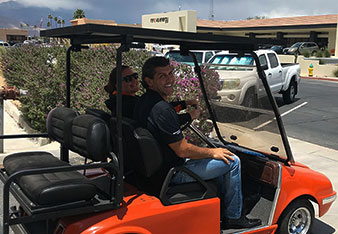 Vince Battaglia on a golf cart with an employee.