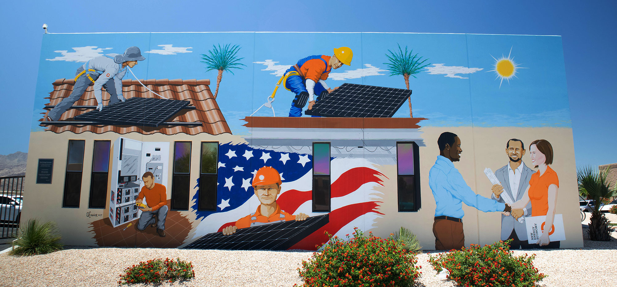 Building painted on the front with a blue sky, some white clouds two palm trees. Also painted on the front of the building is an American flag with one man with a hardhat on holding a solar panel in his hands, 2 men working on the roof installing solar panels. One plane guy facing a man and a woman. The man has development plans in his hand, and the woman has a folder in her arms. There is dirt in front of the building and three bushes for landscaping.