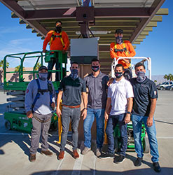 Renova Energy Team Photo of 7 workers during an installation wearing face masks standing under a structure