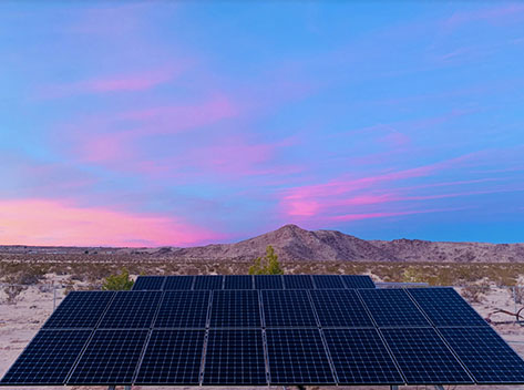 Solar farming in the desert with the beautiful sky and mountains in the background.