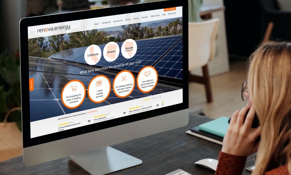 A person views a computer screen displaying a website for Renova Energy. The site features solar panels under a blue sky and has interactive elements like buttons labeled with states and questions related to solar power. The workspace includes a keyboard, notepad, and a cup.