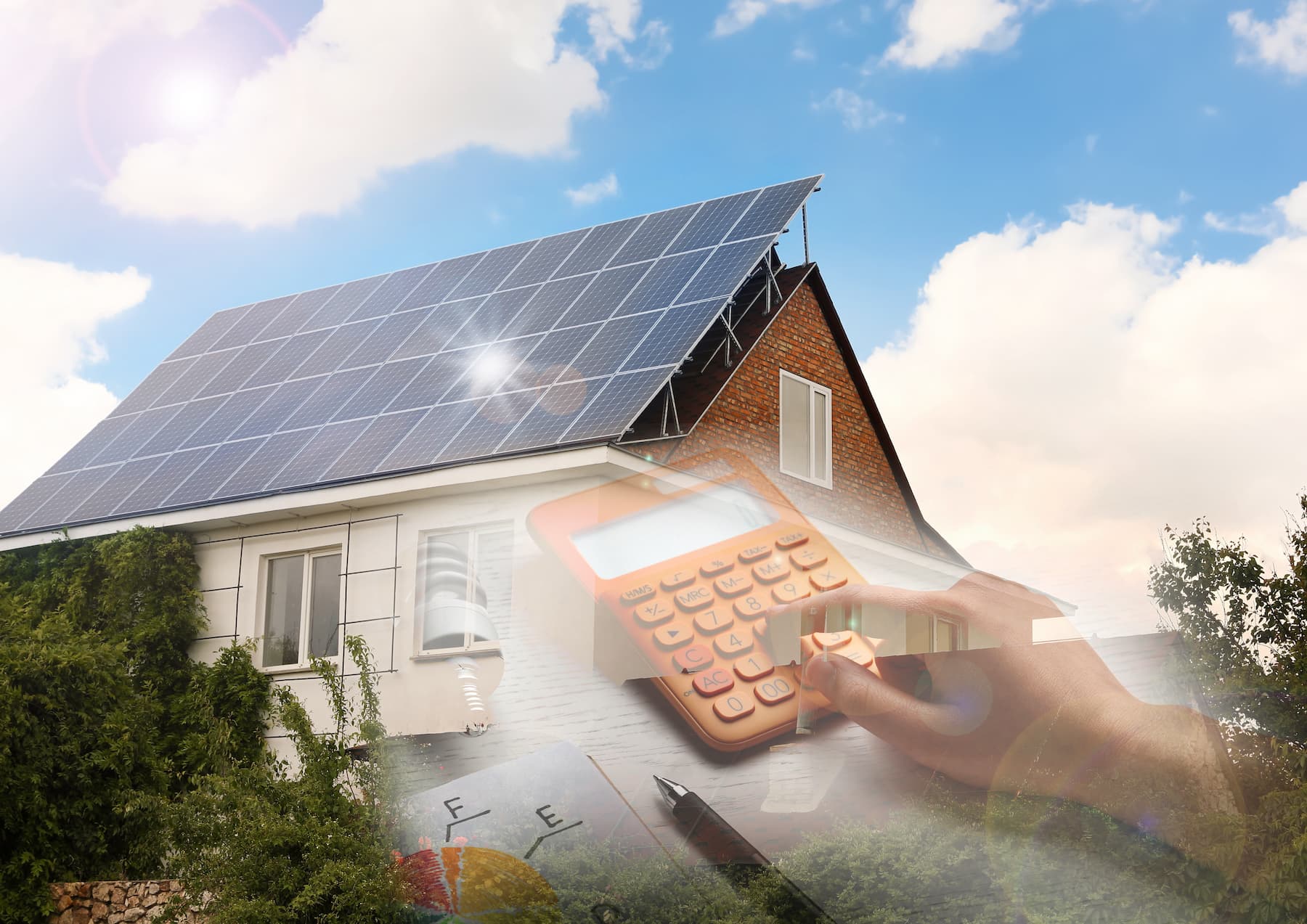 A modern house with solar panels on the roof under a bright blue sky with clouds. In the foreground, a person uses a calculator, implying calculations for energy savings or costs associated with solar power. Lush greenery surrounds the house.