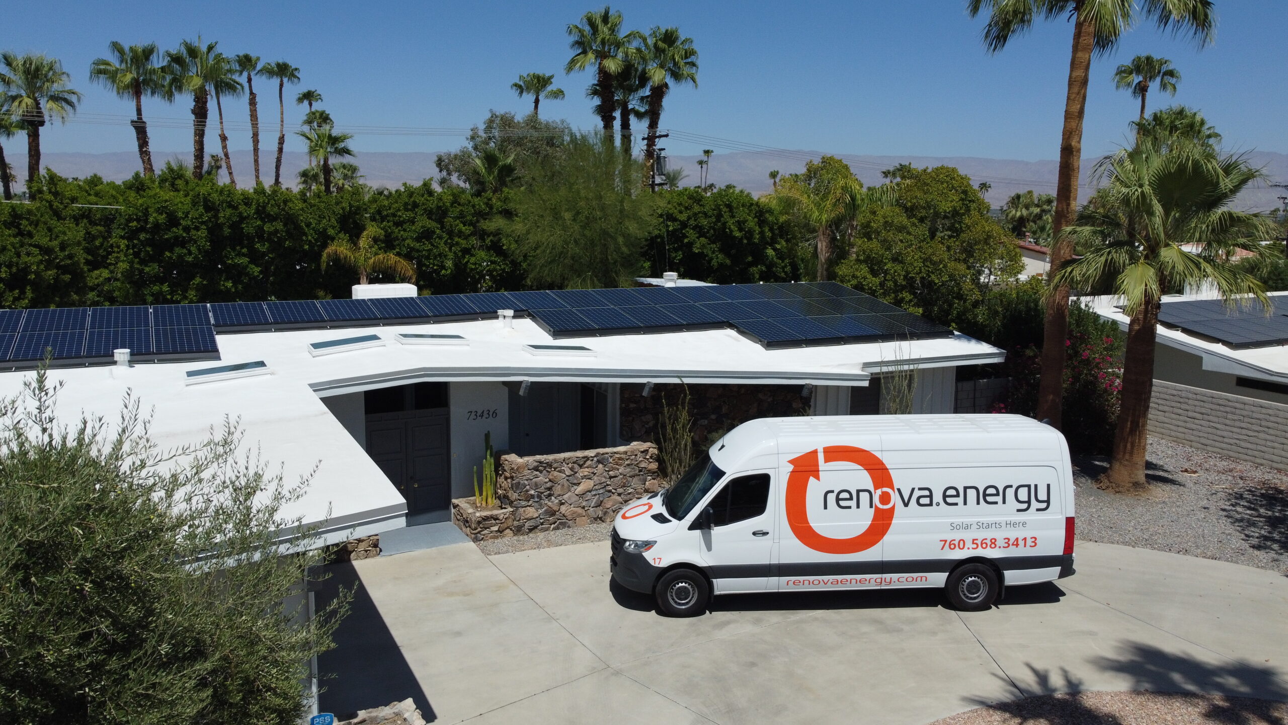 DCIM100MEDIADJI_0413.JPG A white van with renova.energy branding is parked in the driveway of a house with solar panels on its roof, installed by Palm Desert Solar Panel Installers, surrounded by palm trees and a clear blue sky.
